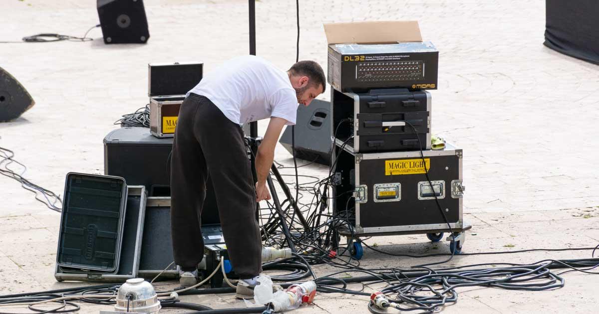 Een cultuurwerker, een geluidstechnicus, aan het werk op een concertpodium.